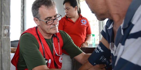 Red cross aid worker checking blood pressure